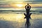 Woman practicing yoga on the beach at sunset in Thailand. Lotus.