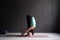 Woman practicing yoga, doing forward bend exercise using wheel, uttanasana pose