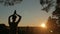 Woman practicing yoga in forest at sunset