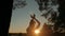 Woman practicing yoga in forest at sunset