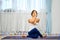 Woman practicing yoga at home, sits with intertwined hands