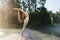 A woman practicing yoga performs an exercise, back bend, Hasta Uttanasana pose, stands on a wooden bridge on a sunny warm morning