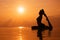 Woman practicing yoga, silhouette on the beach at sunset