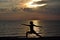 Woman practicing yoga, standing in Virabhadrasana pose at sunset