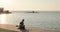 Woman practicing yoga stretching legs and spine sitting on mat on river pier.