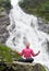 Woman practising yoga on stone in front of beautiful Balea waterfall in Romania