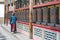 Woman Is Praying By Rotating Cylinders In Buddhist Temple