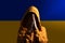 A woman prays against the background of the Ukrainian flag. Prayer for an end to Russia`s war against Ukraine