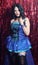 Woman Preforming Burlesque on Stage. Blue Corset Costume With Red Background