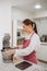 Woman prepares dough using kitchen mixer, pouring ingredients into steel bowl. Cooking homemade cake