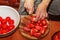 A woman prepares fresh healthy juice from tomatoes. Female hands cut vegetables on a wooden kitchen board. Diet concept for a