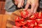 A woman prepares fresh healthy juice from tomatoes. Female hands cut vegetables on a wooden kitchen board. Diet concept for a