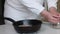 A woman prepares kozinak from nuts. Pour sunflower seeds and peanuts into the pan. Medium plan