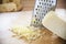 Woman preparing cheese for cook using cheese grater in the kitchen