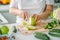 Woman preparing food in her kitchen. Female chopping fresh green apple on cutting board in light kitchen. Healthy eating