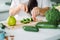 Woman preparing food in her kitchen. Female chopping fresh green vegetables on cutting board in light kitchen. Healthy