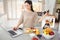 Woman preparing fruit juice while working on laptop