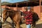 Woman preparing horse for walk - putting on a saddle and bridle