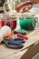 Woman preparing liquid green and red Easter cold colour color in glass in domestic kitchen next to orange, yellow, blue dye in