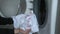 Woman preparing and putting dirty white t-shirt to washing in washing machine.