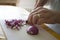 Woman preparing red onion for lunch. Cutting it on white cutting board