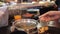 Woman is preparing seafood soup in a buffet against the background of a moving conveyor with plates