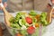 Woman preparing tasty fresh  salad in bowl at table, closeup