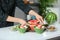 Woman preparing tasty salad with watermelon in kitchen