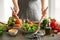 Woman preparing tasty vegetable salad in kitchen