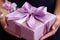 A Woman presenting a beautifully adorned pink gift box with a pretty bow