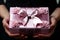 Woman presenting a beautifully adorned pink gift box with a pretty bow and small roses