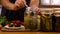 A woman is preserving vegetables in the kitchen. Selective focus.