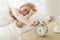 Woman Pressing Button Of Alarm Clock On Night Table