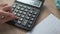 Woman is pressing a calculator to calculate monthly savings to account for monthly income and expenses.	