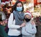 Woman and preteen boy in protective masks standing at Christmas fair