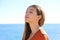 Woman profile portrait breathing deep fresh air on the beach with the ocean on background