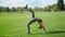 Woman with prosthetic leg doing yoga in field. Girl standing in bridge pose