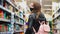 Woman in protecting mask in shop. girl walks around grocery store. Pandemic N1H1 coronavirus virus protection Quarantine purchases