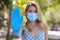 Woman in protective face mask showing stop gesture outdoors, focus on hand. Prevent spreading of coronavirus