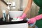 Woman in protective gloves cleaning bathroom