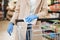 Woman with protective gloves wipes the shopping cart handle with a disinfecting cloth in the supermarket