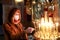 Woman in protective mask with candle in church