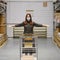 A woman in a protective mask with a cart in a shop. A girl in a store warehouse during a coronavirus epidemic, concept