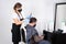 A woman in a protective mask on her face cuts hair to a man in a black mask on her face in a hairdressing salon