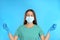 Woman in protective mask meditating on light blue background. Dealing with stress caused by COVIDâ€‘19 pandemic