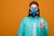 woman in protective medical equipment with antiseptic in hands medical mask on face on a yellow background, coronavirus pandemic