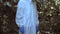 Woman in protective uniform standing in polluted forest front plastic landfill