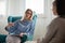 Woman psychotherapist consults patient sitting in armchair at