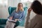 Woman psychotherapist consults patient sitting in armchair at