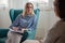 Woman psychotherapist consults patient sitting in armchair at